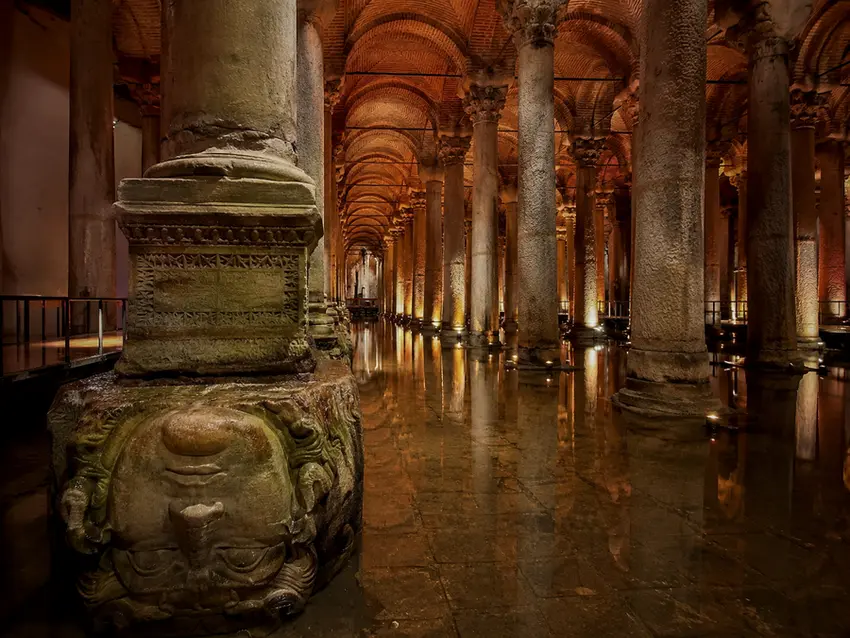 Refleksi kolom-kolom marmer Basilica Cistern Istanbul di permukaan air dengan pencahayaan dramatis berwarna kemerahan