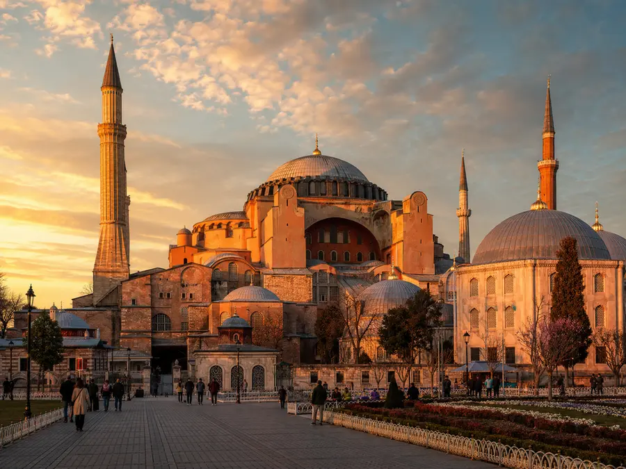 Eksterior Hagia Sophia Istanbul saat golden hour dengan cahaya keemasan memantul di dinding batu berusia ribuan tahun