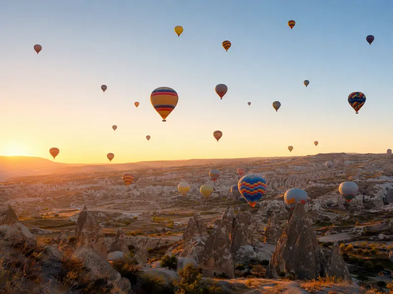 Puluhan balon udara melayang di atas fairy chimneys Cappadocia saat matahari terbit
